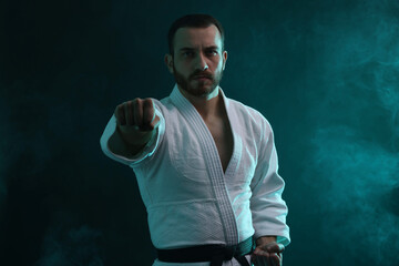Karate fighter wearing uniform in color lights and smoke