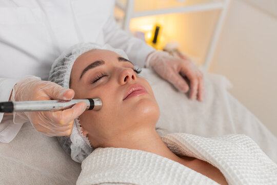 Injection-free mesotherapy or electroporation. Beautician doctor makes client woman face therapy in beauty clinic salon. Girl skin care anti-age spa procedure. Aesthetic cosmetology. Horizontal video