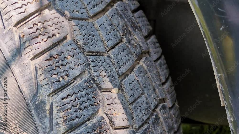 Poster the tire of the car. a part of the tread is visible, which has a complex and clearly defined pattern