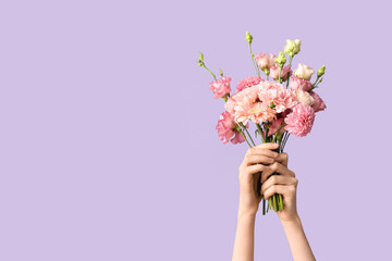 Female hands with beautiful bouquet of flowers on purple background