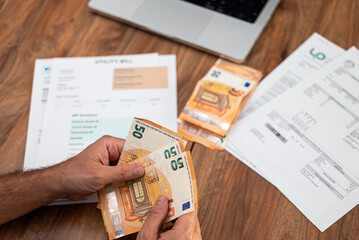 Naklejka premium Mature man hands with euros bills fan over printed utility bills on office table closeup, middle aged company accountant counts financial expenses for household works