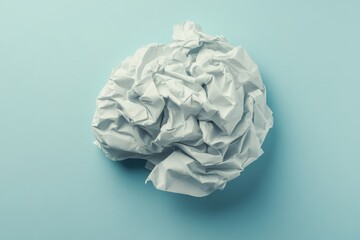 Fototapeta premium Crumpled Paper Ball on Light Blue Surface