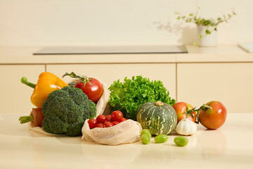 Front view of freshly harvested organic vegetables, including green plants, cauliflower, squash, tomatoes and bell peppers. Presenting on white kitchen countertop, daylight shining on objects.