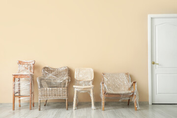 Wrapped chairs with stretch film near beige wall in room on moving day