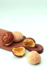 choux au craquelin pastries, some whole and some halved, are arranged on a wooden board against a light background