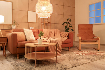 Interior of stylish living room with brown sofa, coffee table and glowing lamps at evening