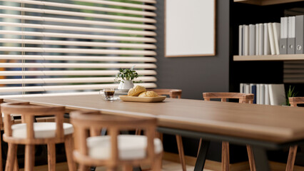 The bread on plate and coffee cup on wooden table with armchairs next to window in office break room