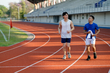 Two asian athlete men or male friends are running together on racetrack in the sports stadium.