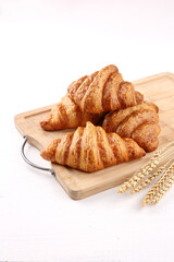 four butter croisants on a wooden cutting board, isolated in white background