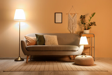 Interior of stylish living room with grey sofa, pouf and glowing lamps at evening