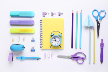 Composition with clock, notebook and school stationery on white background