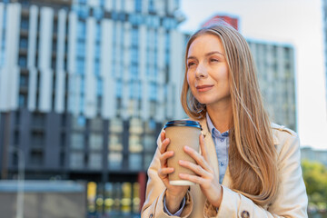 Happy mature businesswoman enjoying morning coffee hot drink and smiling outdoors. Relaxing, taking...