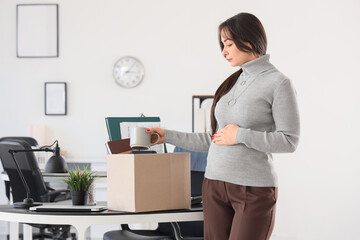 Fired pregnant businesswoman packing personal stuff in office