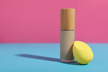 Yellow makeup sponge and bottle of foundation on colorful background
