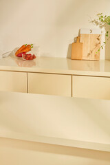 A modern kitchen corner with beige as the main color, soft and warm natural light. The kitchen cabinet surface is made of glossy material, slightly reflecting the objects placed above.