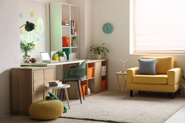 Interior of teenager's room with workplace, shelf unit and armchair