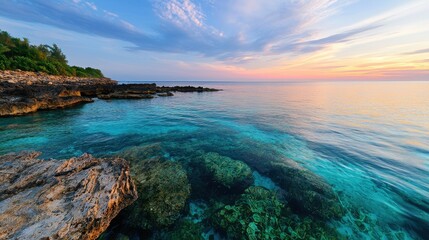 Fototapeta premium Serene Tropical Seascape at Sunset with Crystal Clear Waters and Rocky Shoreline in Tranquil Coastal Environment