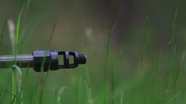 Camouflaged shooter fires precise slow motion shot from grassy woodland position