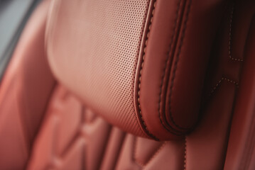 Car leather seat head rest - close-up view. Clay red leather seat in modern car - selective focus.
