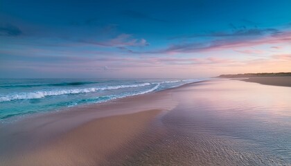 Obraz premium A wide, empty beach at dusk, with gentle waves lapping against the shore and the sky glowing in soft pastel colors.