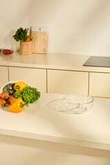 Empty clear glass bowls placed on the kitchen counter. Fresh carrots, bell peppers and pumpkins harvested from the farm. Cozy kitchen space, full of natural light. Photo for design key visual layout.