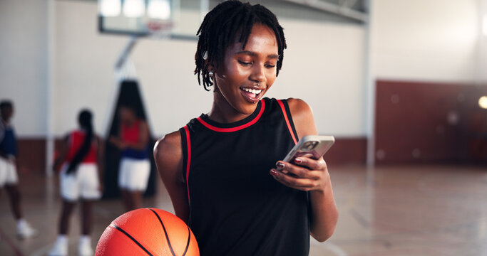 Phone, smile and sports with basketball player on court for app, communication or social media. Break, fitness and training with happy woman in gymnasium for competition, exercise or performance