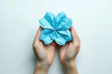 Hands holding a light blue origami flower.