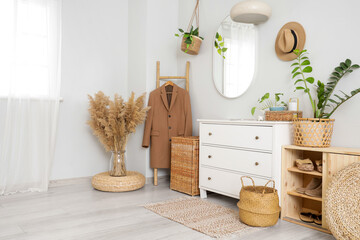 Interior of stylish hallway with mirror, coat and wicker baskets