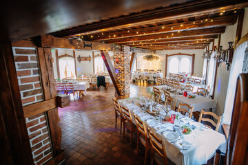 Rustic wedding reception hall with wooden beams, fairy lights, elegant table settings, and a glowing head table centerpiece. Copy space included..