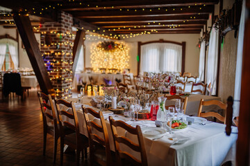 Cozy wedding reception venue with rustic wooden beams, fairy lights, and elegantly set tables decorated with flowers and refreshments..