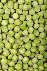 A close-up, top-down shot shows a dense layer of frozen green peas, some with visible ice crystals