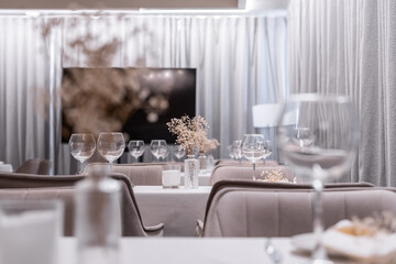 beautiful table decoration in restaurant. festive table setting in restaurant. white tablecloth on table, wine glasses, white plates, flowers in vase, candles are burning. romantic atmosphere