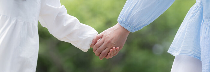 Image of a parent and child holding hands with affection, etc. on a fresh green background Banner of a close-up of a hand without a face