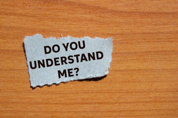 Do you understand me message written on ripped torn grey paper piece on wooden background....