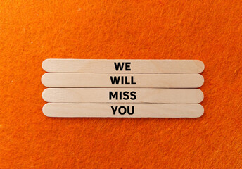 We will miss you message written on wooden sticks on orange background. Conceptual we will miss you symbol. Copy space.