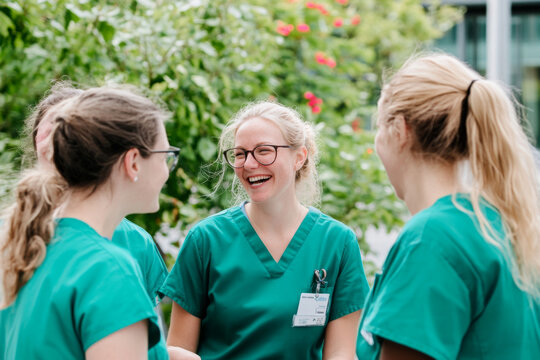 Group of female doctors laughing together outdoors, background