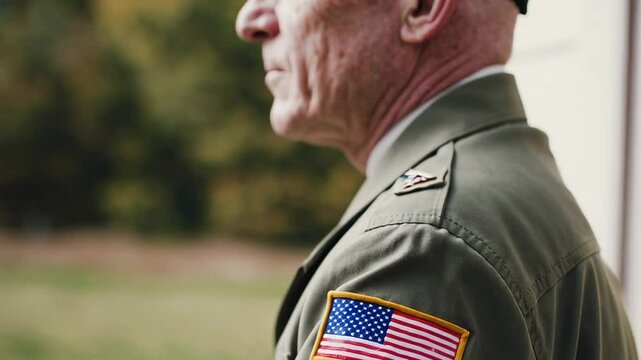 Close up profile view of a senior military veteran in uniform, solemnly displaying the american flag patch on his shoulder, evoking themes of service, patriotism, and remembrance