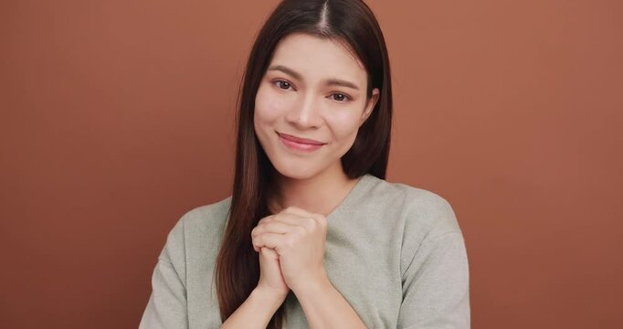 Young woman shows signs of begging for mercy in need of something. Isolated on brown background in studio.