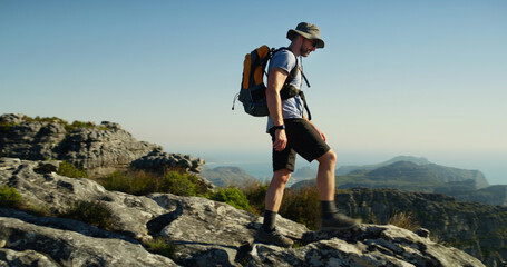 Hiking, mountain and cliff with man in nature for fitness, travel adventure and workout. Blue sky,...