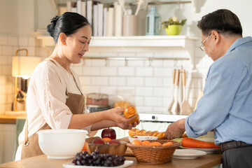 Asian senior couple cooking breakfast in the kitchen. husband helping wife on the morning weekend. Retired people enjoying lifestyle at the preparing counter