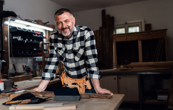 Portait of smiling carpenter in his workshop looking at camera.