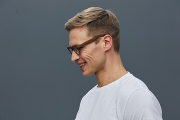 smiling man wearing glasses white t-shirt side profile look down isolated on gray background casual style mental health and gadgets concept