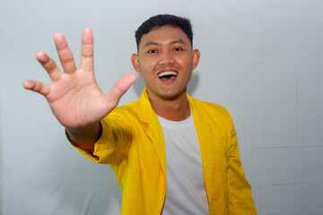 confident young asian man wearing yellow suit making rejecting gesture