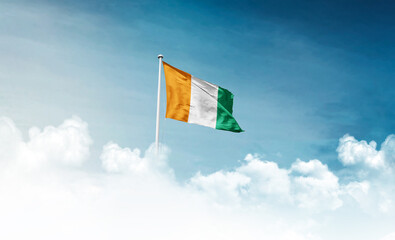 Ivory Coast national flag with mast waving in beautiful sky. Ivory Coast flag for Republic Day and...