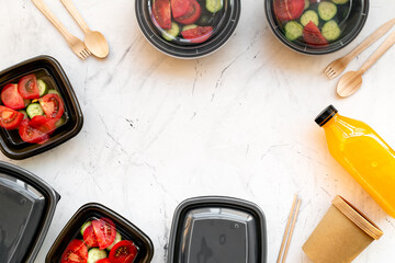 Tomatoes salad in lunch boxes with orange juice in a bottle and disposable cutlery, top view