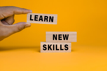 male hand put wooden blocks with learn new skills words text isolated on orange background