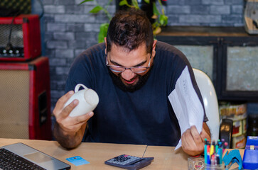 Young man yelling to a credit card about to break a coffee cup