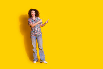Fototapeta premium Young woman with curly hair gesturing happily on a vivid yellow background wearing trendy casual clothes including a printed shirt