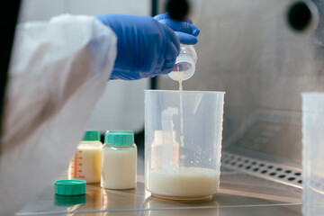 Pouring donor milk into measuring container in sterile lab