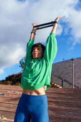 Mature woman performing stretching exercises with resistance band in a city park, promoting healthy lifestyle and fitness
